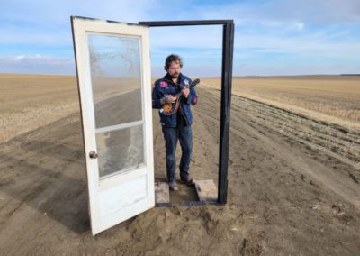 Kit Langfield in doorway with mandolin for music video.